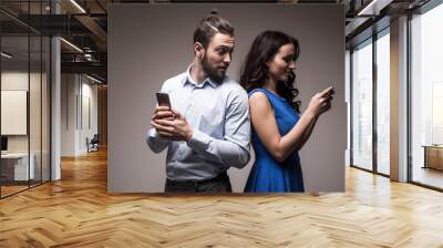 Attractive couple using their smartphones on white background Wall mural